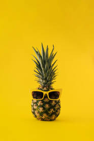 Svježi ananas sa žutim plastičnim sunčanim naočalama.