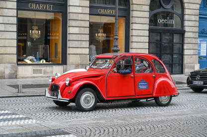 Ljudi se voze u oldtimeru u gradu. Stari crveni Citroen na ulici. Citroën 2CV