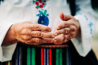Ruke starije žene u tradicionalnoj narodnoj nošnji.