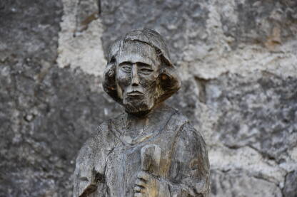 Drvena statua čovjeka sa kamenim zidom koji se nalazi u pozadini na tvrđavi u Jajcu.
