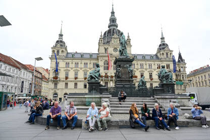 Graz, Austrija: Grupa ljudi na glavnom trgu u centru grada. Historijske građevine na glavnom trgu ili Hauptplatzu. Stari grad Graz. Erzherzog-Johann-Brunnen fontana.
