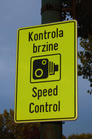 “Saobraćajni znak ‘Kontrola brzine’ na žutoj tabli, postavljen uz cestu. Oznaka upozorava vozače na nadzor brzine i pojačanu sigurnost saobraćaja.
