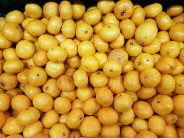 Mandarine u gajbi na polici u prodavnici; kisele mandarine za prodaju.