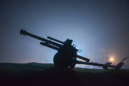 Silueta artiljerijskog topa noću u magli. Stari top u ratnoj zoni.