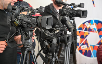 Kamere na konferenciji za novinare. Snimanje press događaja video kamerom. Novinarstvo. Profesionalni snimatelj kamerom snima intervju.