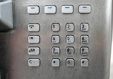 Brojevi na telefonu u javnoj govornici. Metalna telefonska tipkovnica, krupni plan. Stara telefonska kabina.