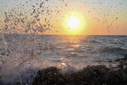 Morski valovi na plaži. Prekrasan zalazak sunca na moru. Morska obala. Kapljice morske vode.