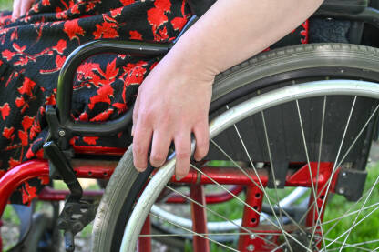 Žena u invalidskim kolicima. Djevojka sjedi u invalidskim kolicima u parku. Invaliditet. Osobe sa invaliditetom. Rehabilitacija
