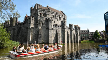 Gent, Belgija: Dvorac uz riječni kanal u centru grada. Utvrđene kule i zidine na srednjovjekovnom utvrđenju. Turisti na brodicama.