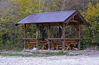 Natkriveno sklonište, za izlete u prirodi, sa stolom i stolicama od drveta.