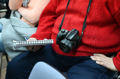 Novinar sa fotoaparatom drži notes u ruci. Press konferencija.