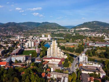 Zenicu, Bosna i Hercegovina, snimak dronom. Zgrade, ulice, parkovi i stambene kuće. Centar grada Zenice, pogled odozgo. Gradski pejzaž.