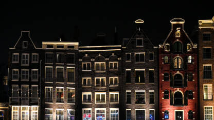 Amsterdam, Holandija. Tradicionalne kuće u gradu Amsterdamu noću. Tipične holandske kuće sa šarenim fasadama.