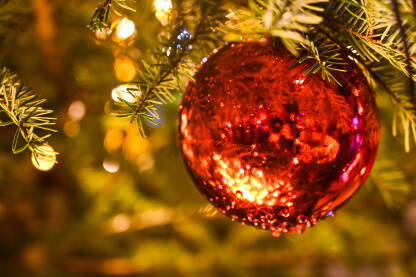 Sjajna kuglica, izbliza. Okićeno novogodišnje i božićno drvce kod kuće. Šareni ukrasi i upaljene lampice na drvcu. Sretna Nova godina.