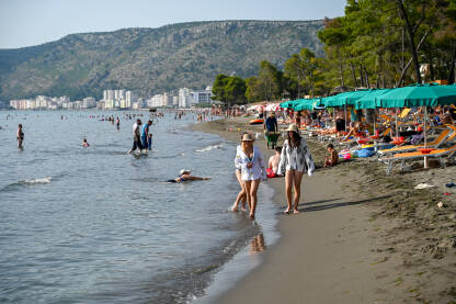 Shëngjin, Albanija. Ljudi plivaju u moru i sunčaju se na plaži. Turisti na ljetnom godišnjem odmori. Popularna turistička destinacija na Jadranskom moru u Albaniji.