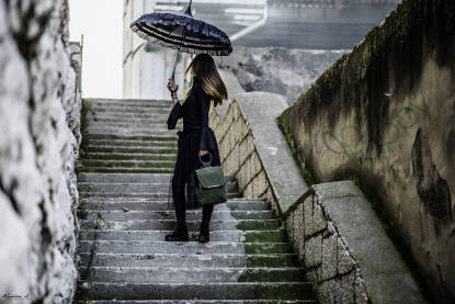 Žena na stepenicama s kišobranom i torbom