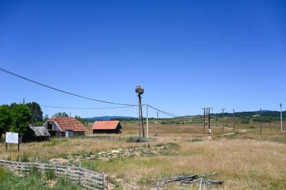 Panoramski pogled na selo s kućama, štalama i gnijezdom bijele rode (Ciconia ciconia) izgrađenim na banderi. Seoski pejzaž.