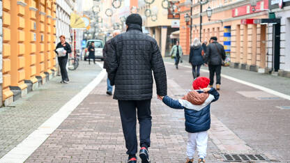 Muškarac šeta ulicom sa dječakom. Samohrani roditelji. Otac i sin.