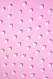 Kocke šećera razbacane na svijetloj roze podlozi sa sjenkama kreiraju 3d izgled.
