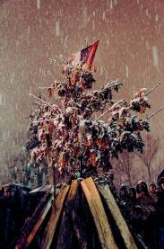 Pravoslavni vjernici okupljeni oko badnjaka. U pozadini zastava Srpske pravoslavne crkve, Snijeg koji pada dodatno stvara bajkovitu atmosferu ovog vjerskog običaja. Duga ekspozicija.