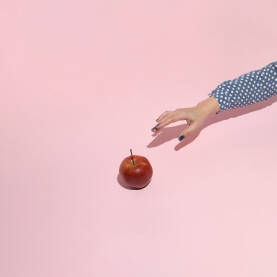 Ženska ruka poseže za svježom jabukom.