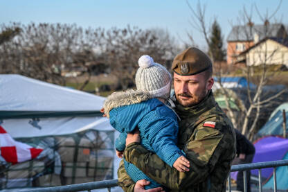 Poljski vojnik nosi izbjegličko dijete iz Ukrajine.