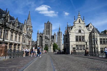 Gent, Belgija: Ljudi šetaju ulicom u centru grada. Crkva i zvonik.
