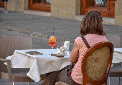 Žena pije piće u restoranu/kafiću. Žena sjedi sama i pije kafu i osvježavajuće piće.