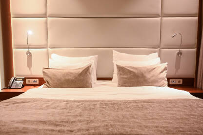 Krevet u hotelskoj sobi. Smještaj. Jastuci i prekrivač na velikom krevetu. Odmor.