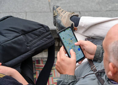 Čovjek koristi mapu na svom mobilnom telefonu. Turisti koriste Google mape na pametnom telefonu za orijentaciju. Čovjek koji istražuje grad.