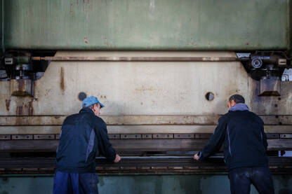 Radnici na industrijskoj presi za metal