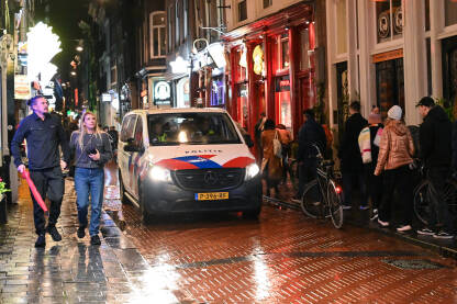Holandska policija patrolira u gradu Amsterdamu. Holandska policija patrolira u gradu Amsterdamu. Kombi Nizozemske policije. Ljudi šetaju gradom.