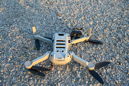 Srušen i oštećen dron na asfaltu. Slomljeno kućište i kamera drona. Dron pao na zemlju. Nesreća tokom leta.