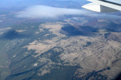 Pogled na planine kroz prozor aviona. Planina Vlašić iz zraka. Putovanje avionom.