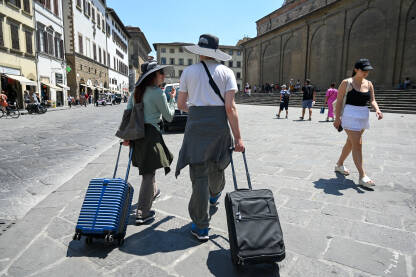 Turisti sa koferima u gradu. Ljudi putuju. Firenza, Italija, grupa ljudi na trgu.