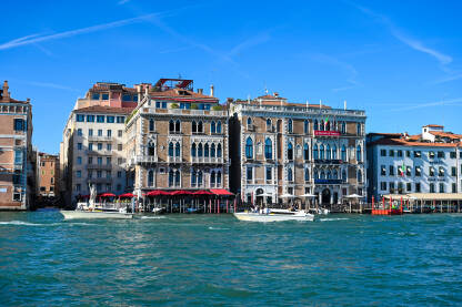Venecija, Italija: Historijske zgrade uz riječni kanal. Čamci i gondole na vodi. Popularno turističko odredište.