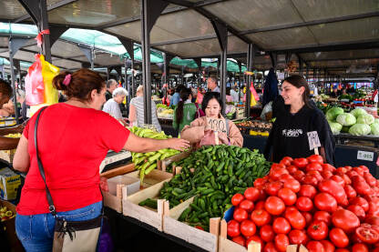 Djevojke kupuju svježe povrće na pijaci. Prodaja voća i povrća.