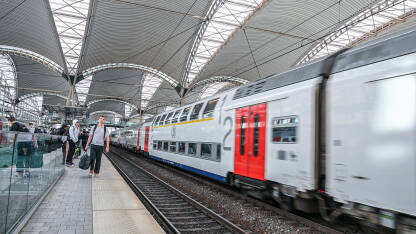 Putnici sa torbama na željezničkoj stanici. Dvospratni voz na stanici. Putovanje vozom.