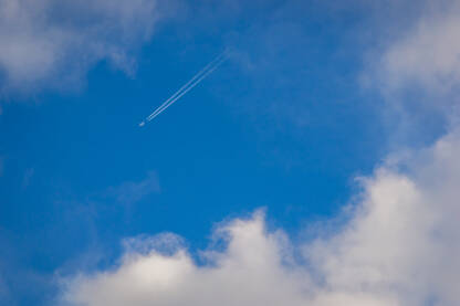 Svijetlo plavo nebo sa oblacima i tragom aviona