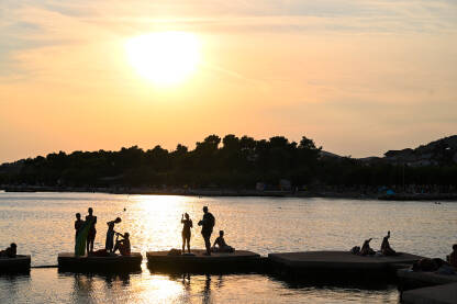 Siluete ljudi na moru tokom zalaska sunca. Turisti na godišnjem odmoru.