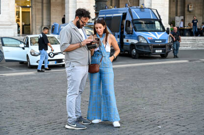 Rim, Italija: Turisti gledaju u mapu na telefonu. Ljudi u gradu. Muškarac i djevojka na trgu.