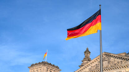 Njemačka zastava vijori na vjetru. Zastavu Njemačke na jarbolu ispred Bundestaga u Berlinu.