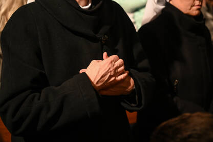 Časna sestra moli prekriženih ruku u katedrali. Božićna misa polnoćka. Katoličanstvo.