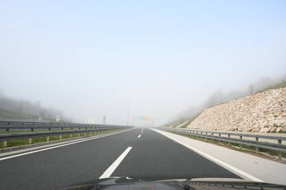 Magla na putu. Vožnja na autoputu po maglovitom vremenu. Teški uslovi vožnje. Pogled na cestu kroz vjetrobransko staklo automobila. Pogled vozača.
