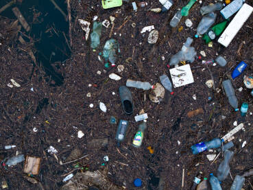 Razni oblici komunalnog otpada nagomilani u rijeci Drini, vidljivi na površini i uz obalu.