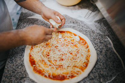 Kuhar stavlja sir na pizzu