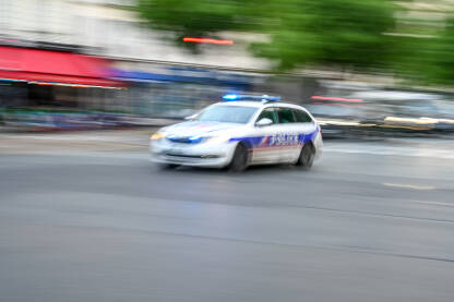Zamagljena policijska patrola se brzo kreće ulicom. Pogled sa strane na policijski automobil u Francuskoj. Policijsko patrolno vozilo.