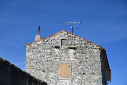 Stara kamena kuća sa TV antenom na krovu.