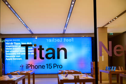 Izlog Apple trgovine u gradu noću. Reklama za novi iPhone 15. Titanium. Prodavnica pametnih telefona reklamira novi model telefona.