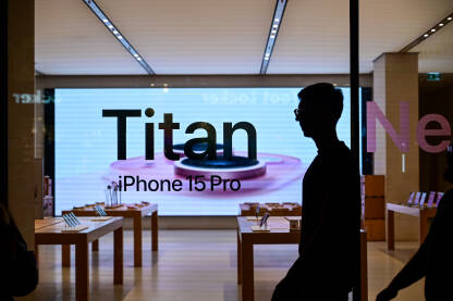 Izlog Apple trgovine u gradu noću. Reklama za novi iPhone 15. Titanium. Prodavnica pametnih telefona reklamira novi model telefona.